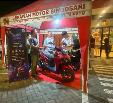 Pengunjung melihat motor di bawah tenda merah