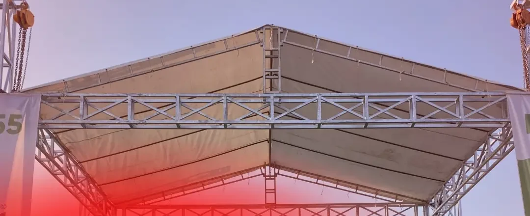 Panggung beratap dengan rangka truss dan banner P55 berdiri di lapangan